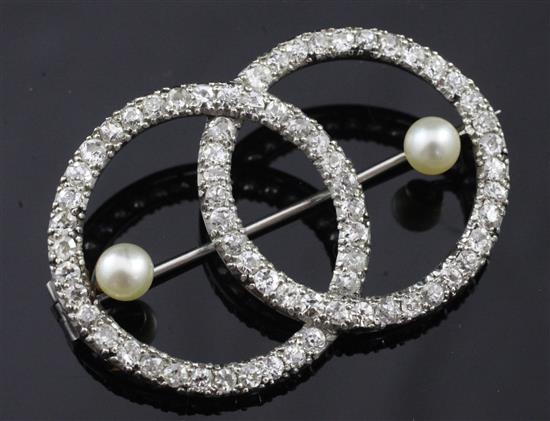 An early 20th century platinum, diamond and pearl openwork twin circle brooch, 1.75in.